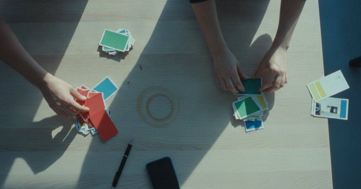 Manos clasificando tarjetas de contenido impresas en montones sobre una mesa